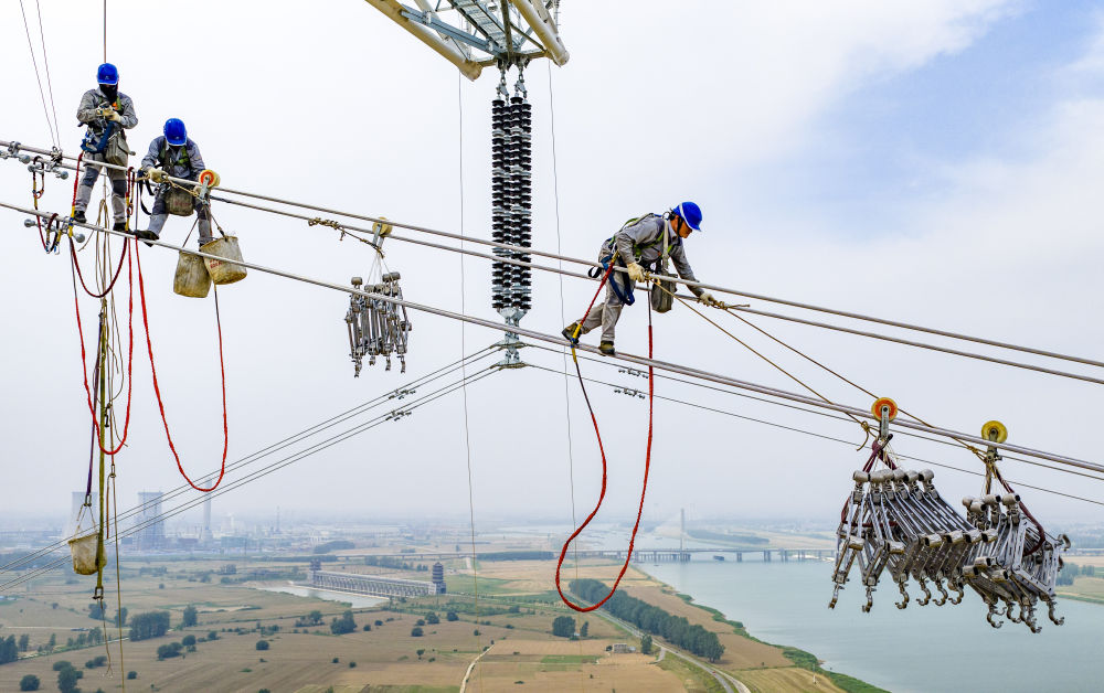 2025年6月11日，在安徽省滁州市凤阳县淮河边，安徽送变电工程有限公司施工人员在百米高空进行淮河大跨越作业（无人机照片）。新华社记者 刘军喜 摄.jpg